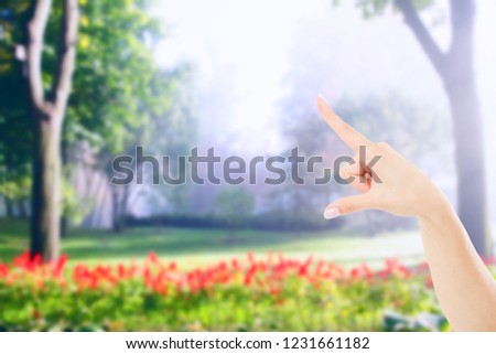pointing female hand on blurred garden or park background, mock up