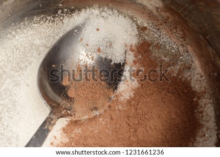 Spoon lays in a pot with sugar and cocoa powder. Preparing to do cocoa