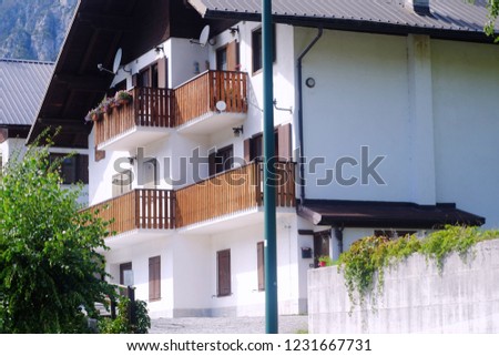 Alpine house with wooden balconies and a brown roof overlooking the theme of alpine buildings and nature
