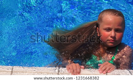 Pretty little girl with long blonde hair swiimming in the pool, closeup