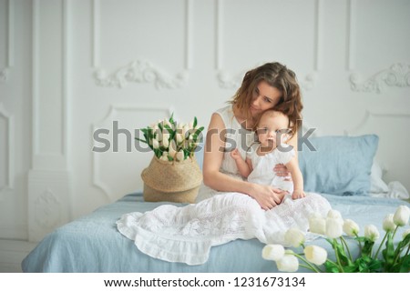 beautiful young mother with baby girl in her arms. The concept of a happy family, motherhood. mother playing with her baby in the bedroom. women's day