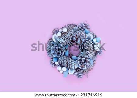 Winter and Christmas wreath with snow covered spruce pine fir, mistletoe, pine cones, cedar isolated on pink background.