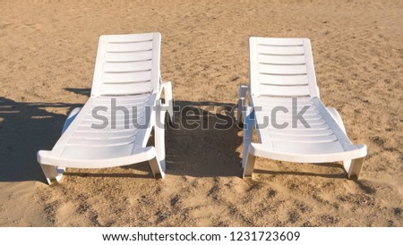 Two sunlongers on the sand beach in summer. Royalty-Free Stock Photo #1231723609
