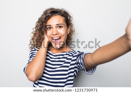 Portrait of a young mixed race  woman taking selfie with mobile phone over gray background