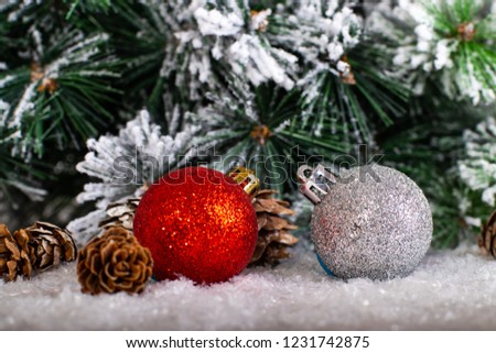 Christmas decoration red and silver balls in a tree with tinsel and pinecone in snow