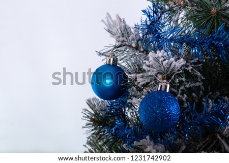Christmas decoration blue and silver balls in a tree with tinsel and pinecone in snow