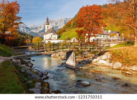 Amazing autumn scenery in Bavarian Alps with bridge above river and famous Parish Church of St. Sebastian in Ramsau bei Berchtesgaden village, Berchtesgadener Land National Park, Bavaria, Germany. Royalty-Free Stock Photo #1231750315