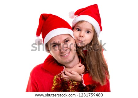 Family cosy xmas time. Daughter and father wearing santa hats and tinsel around the neck. Daughter hugs father around the neck. Landscape image