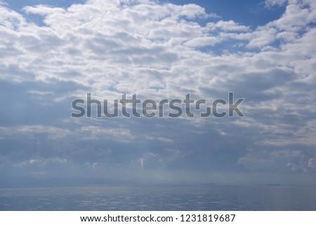 Sea with silver reflection of the sun  with blue sky and clouds in the background