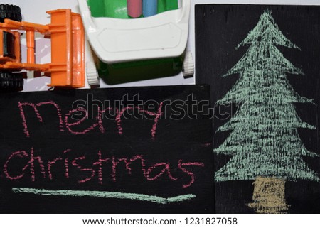 Text Merry Christmas - New Year holiday background - black chalkboard in wooden frame with Hand Drawn Doodle Christmas Tree Chalkand loader kids