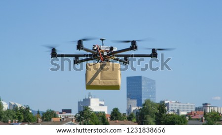 CLOSE UP: UAV drone delivery delivering big brown post package into urban city Royalty-Free Stock Photo #1231838656