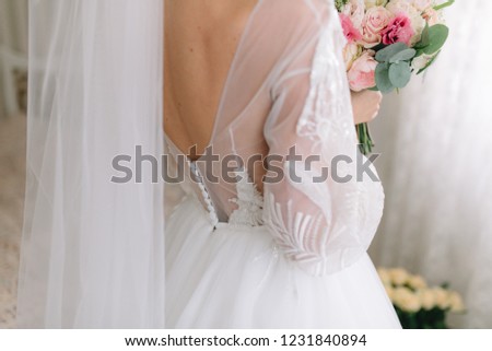 Bride in beautiful dress holds a wedding bouquet.