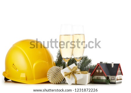 Construction hard hat, fir tree branches, model house,  two glasses with champange and Christmas ornament isolated on a white background. New Year and Christmas. Horizontal view with copy space
