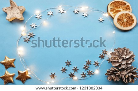 Christmas background with xmas decorations -  sparkle lights in the centre of the blue canvas background. Dried lemon citrus slices ,pine cones, christmas stars in the corners. Merry christmas card.