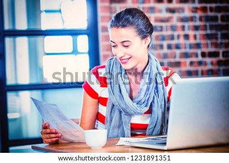 Woman looking at picture chart with laptop on table in office