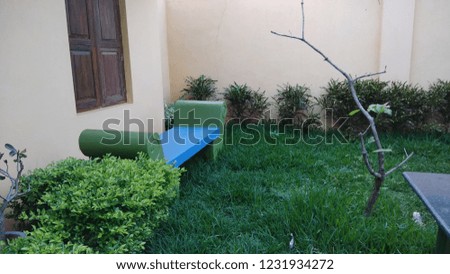 outdoor garden with trees and tiny plants and cement seat around the corner of the garden. 840
