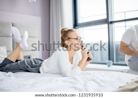 Girl holding a TV remote and watching important news. side view photo. ergent message, news