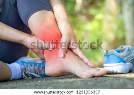 woman hand massaging her leg pain because of twisted ankle broken from exercise  Royalty-Free Stock Photo #1231936357
