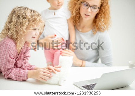 girl with curly hair watching cartoon while her mother is looking after a baby. close up cropped photo