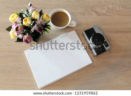 top view notebook and cup of coffee , camera on wooden table office