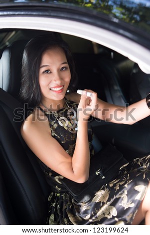 Vertical image of an elegant lady applying lip balm in car