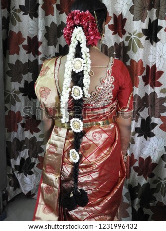 hindu bride showing her back with long hair decorated with rose petals, jasmine flowers and lakshmi devi lockets