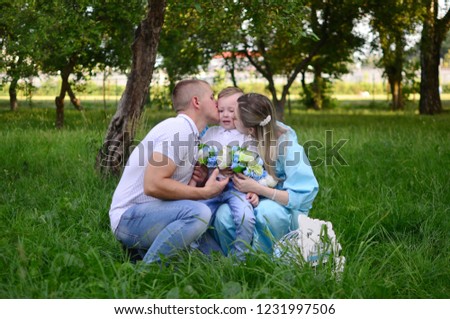 Happy family together in summer garden/park. Parents kissing their son. Outdoor photo