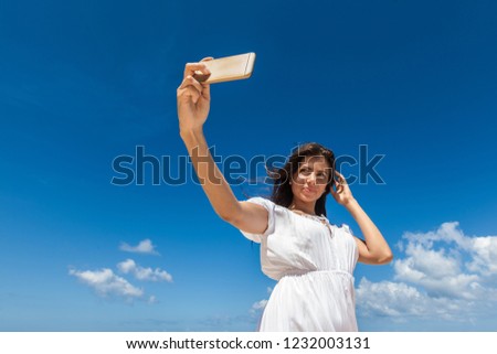 Portrait of a Happy young woman take photos of her self , smile to camera , sky background