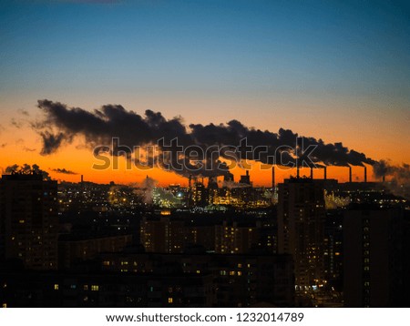 Urban sinrise with industrial facilities and heavy smoke polluting the environment