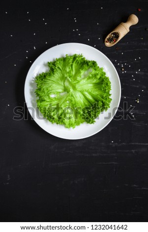 fresh lettuce leaves salad in a white plate on a wooden table background. top view. copy space