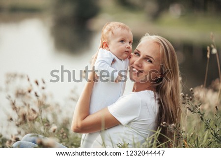 
Beautiful mother with long blond hair walks in the park with the baby. Image with selective focus and toning.