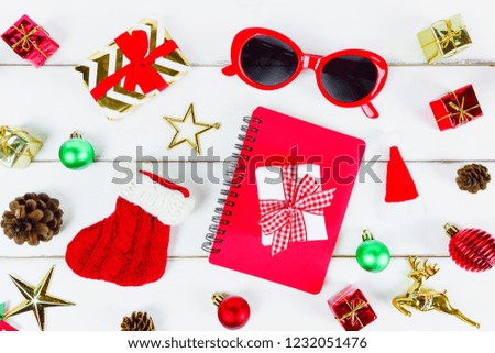 Christmas New year theme object (gift box ,Santa sock, sun glasses, red notebook, star, pine cone, reindeer, Santa hat) decorated on white wooden table desk and background.Holiday festival concept.