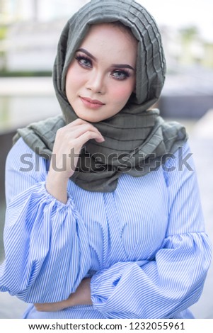 Portrait of a beautiful Asian woman wearing a hijab in a real environment.  Muslim female hijab fashion portraiture concept.