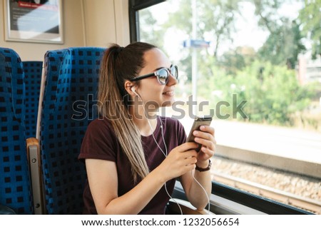 A young girl listens to a music or podcast while traveling in a train.