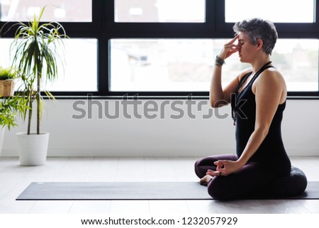 Mature Caucasian woman practicing yoga on living room floor. Middle aged woman doing yoga indoors.