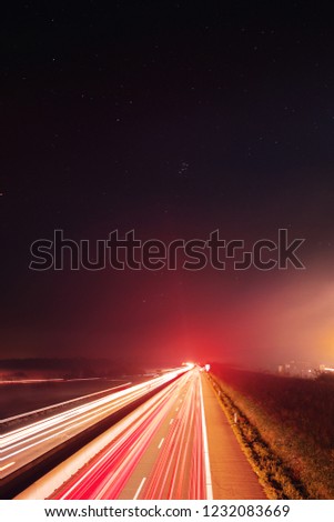 German motorway view with night stars sky and fog that glow from cars light trails showing the speed and motion from the traffic. Braunschweig, Germany