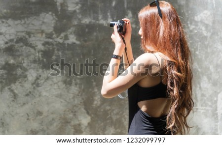 Cheerful photographer young woman with sunglasses holding camera taking photo in city. Traveler young girl use digital camera take photo reflex building while during travel. Photography concept.