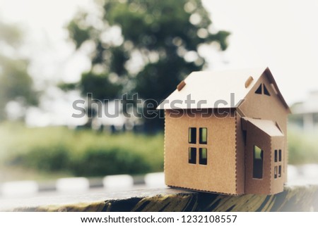 Small model of house with bokeh green background. Copyspace for text or image. 