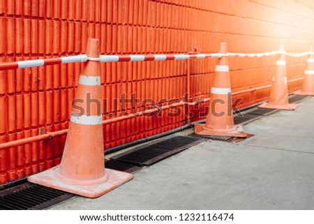 traffic cone, with white and orange stripes on red wall, copy space
