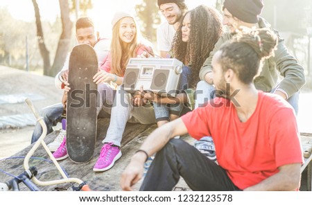 Happy generation z friends listening music and laughing in city park - Young diverse culture people having fun together - Youth, millennial lifestyle, multiracial concept - Focus on african girl face