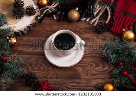 A cup of coffee in the morning after Christmas. The food flat lay shows a spruce branch, Christmas toys and knitted plaid. The photo was taken on the wooden background.