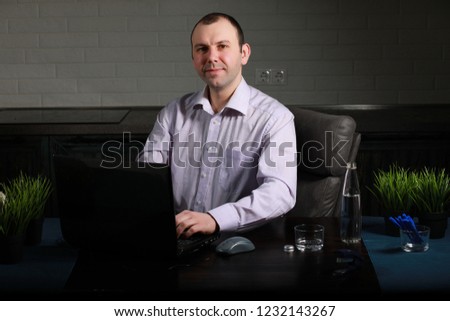 man is sitting at his desk and working on a laptop
