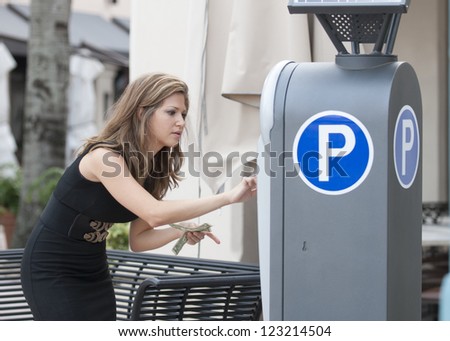 Attractive woman putting money in a parking meter Royalty-Free Stock Photo #123214504