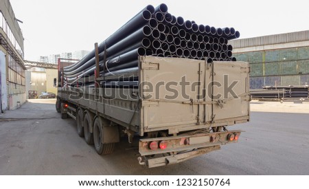 Old truck loaded with black plastic pipes. Back view. Royalty-Free Stock Photo #1232150764