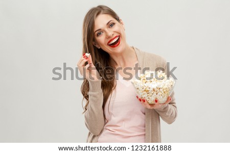 Happy woman eating popcorn, pop corn in glass bowl. Isolated studio portrait on white.
