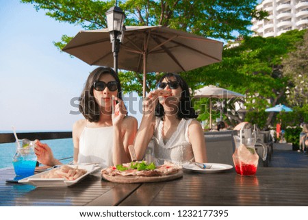 Leisure concept. Beautiful girl is eating at the seaside restaurant. Beautiful girl is enjoying the food on the table.