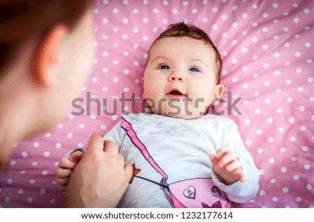 Cute adorable Caucasian newborn three months old baby girl revealing the world. Her mother looking at her with love and care. Born to this world concept image.