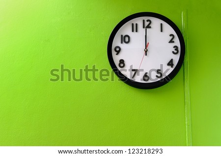 Clock showing 12 o'clock pm on a green wall Royalty-Free Stock Photo #123218293