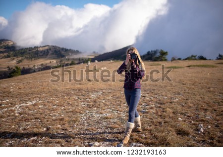 girl photographer in a red shirt walks in the mountains