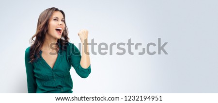 Yes, I have done it! Very happy gesturing woman in green confident clothing, empty copyspace place for slogan or some advertising text message, over grey background. Success in business concept. Royalty-Free Stock Photo #1232194951
